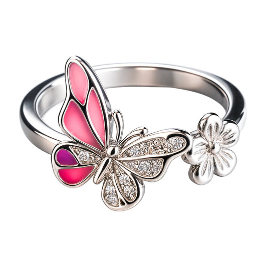 Silver ring with pink butterfly and flower design on a white background