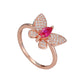 Rose gold butterfly ring with a red gemstone on a marble surface