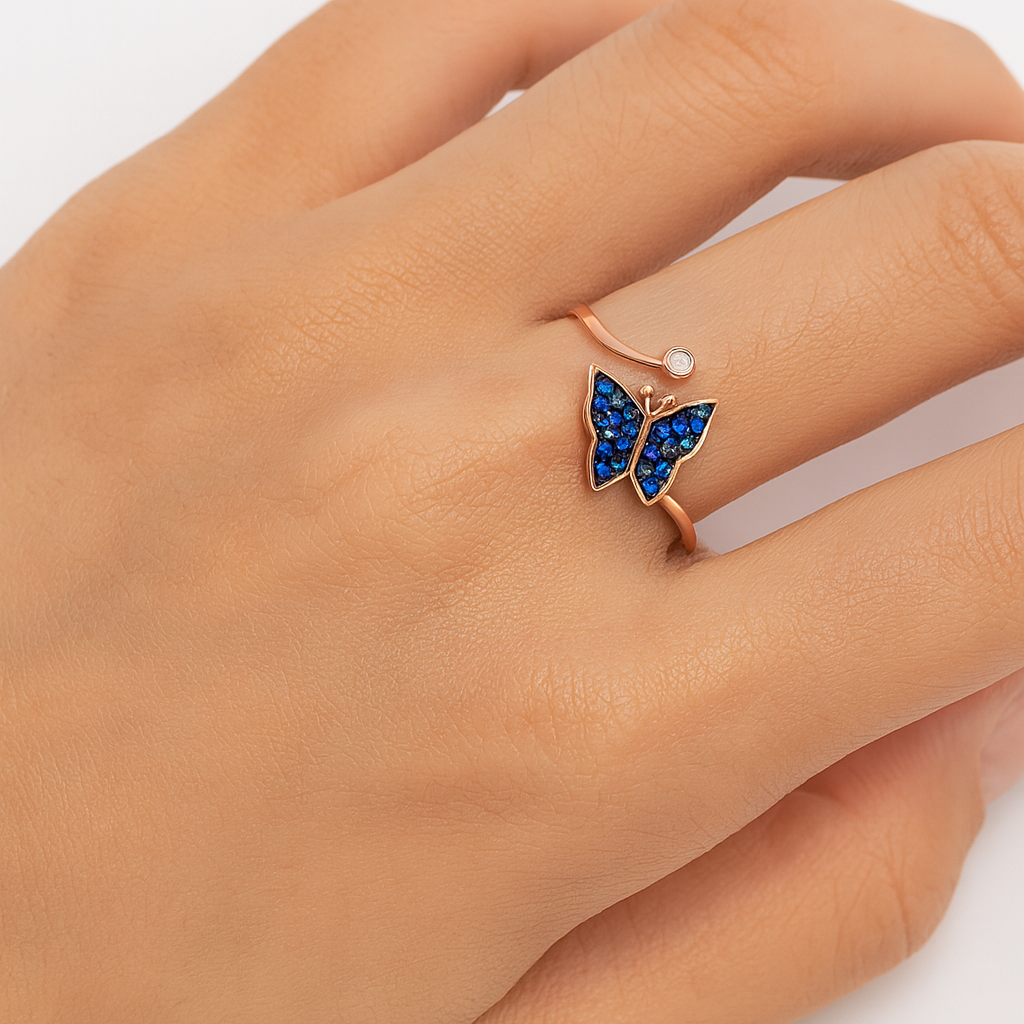Hand wearing a butterfly-shaped ring with blue gemstones on a light background